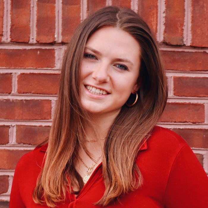 Photo of Riley Davis in front of a brick wall.