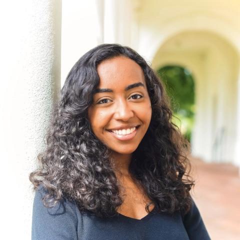 Woman in a black blouse smiling with white columns in the background